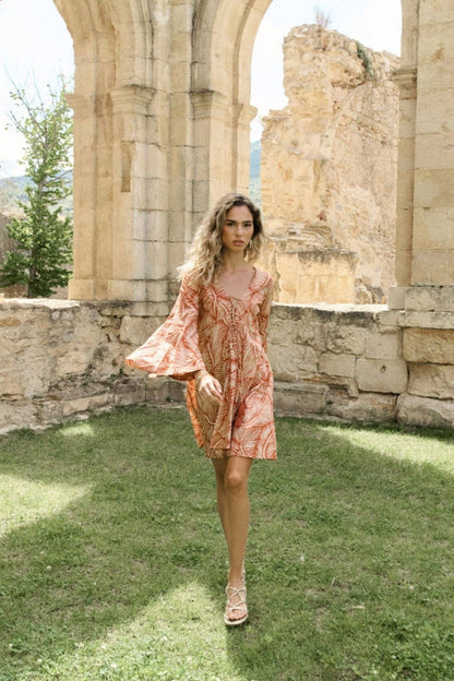 Model läuft in sommerlicher Kulisse im kurzen Viskosekleid mit rot-braunem Muster.